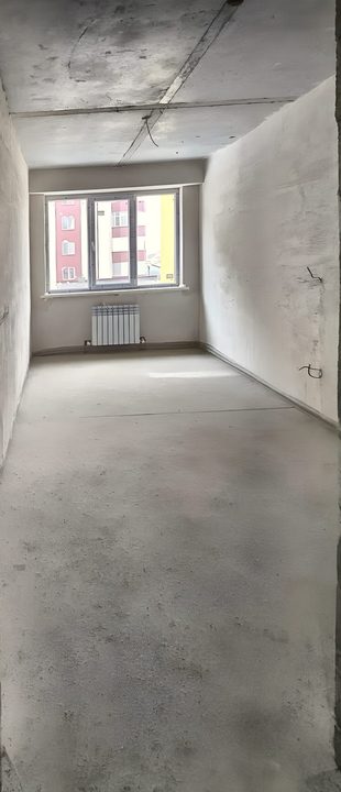 Комната в предчистовой отделке: стяжка на полу, батарея под окном, выровненные стены